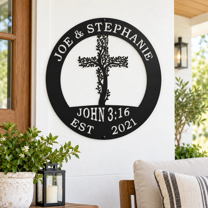 a black metal sign with a tree-like design and text, mounted on a white wall.