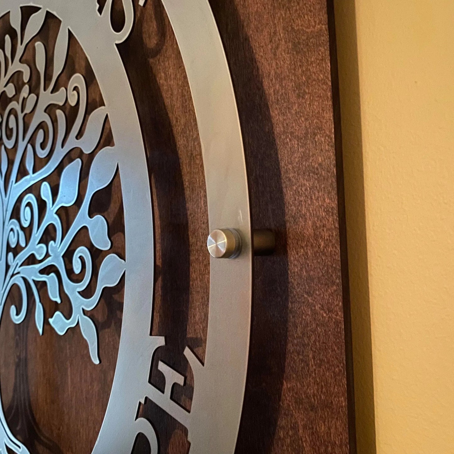 Intricately designed decorative metal wall art mounted using standoff spacers on a wooden background, ideal for personalized home décor or accent wall installations.