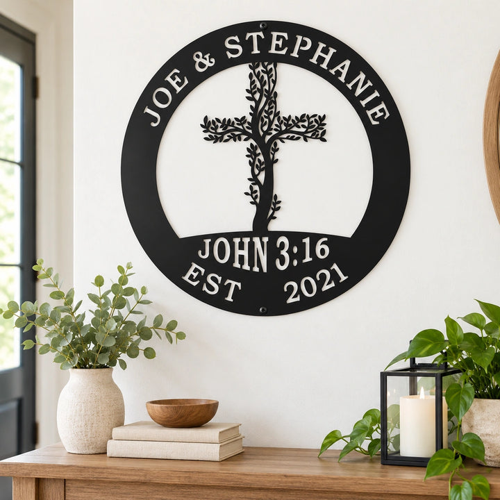 a wall decoration with a tree-like design and a cross, mounted on a wall above a wooden table with various items on it, including a bowl, a candle, and some books.