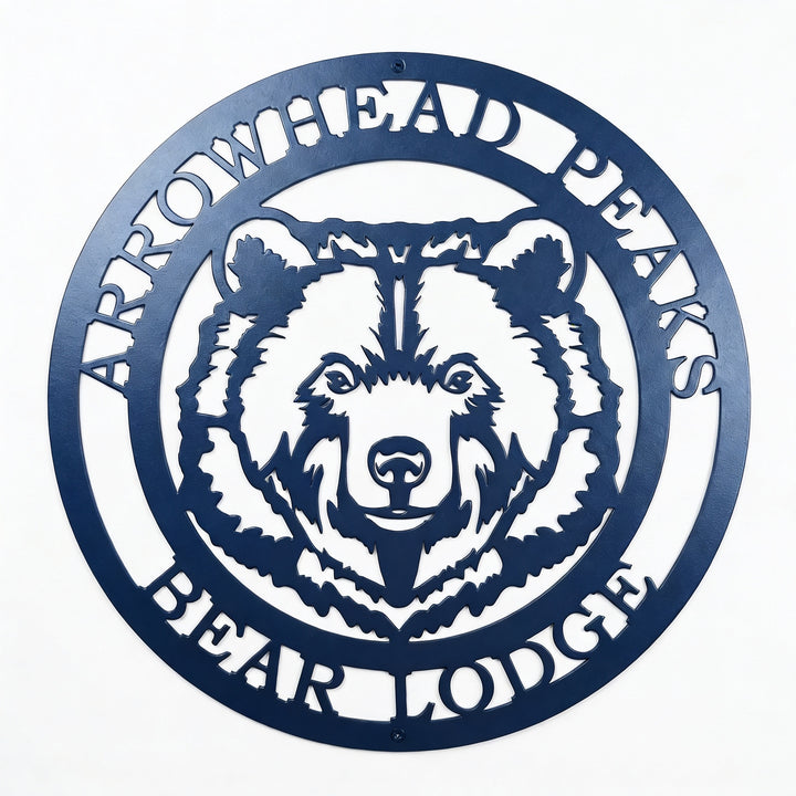 Custom Arrowhead Peaks Bear Lodge metal sign mounted above wooden shelf with books and decorative plants on white shiplap wall