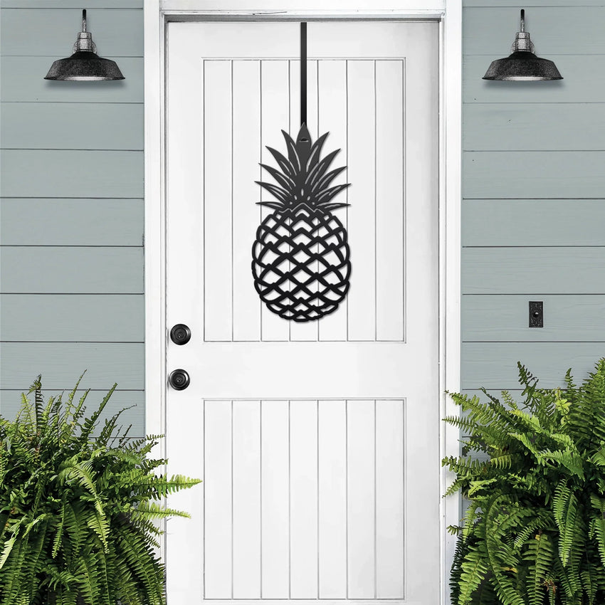 Black pineapple metal welcome wreath mounted on a white front door