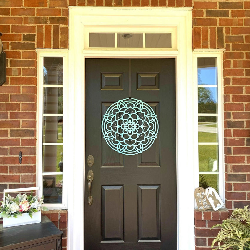 Dark gray front door featuring a decorative white circular lotus flower design mounted on a brick wall, highlighting elegant outdoor metal wall art and durable craftsmanship.