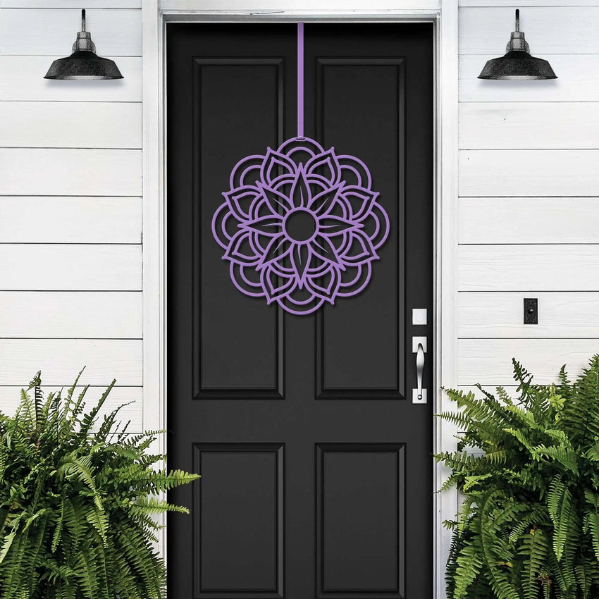 Lavender metal flower wreath on black door, purple floral decor, green plants, white wall exterior, handcrafted outdoor metal sign, elegant entryway art