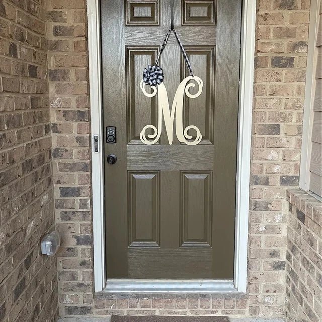 White personalized metal initial door wreath displayed on a brick front door