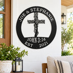 a black metal sign with a tree-like design and text, mounted on a white wall.