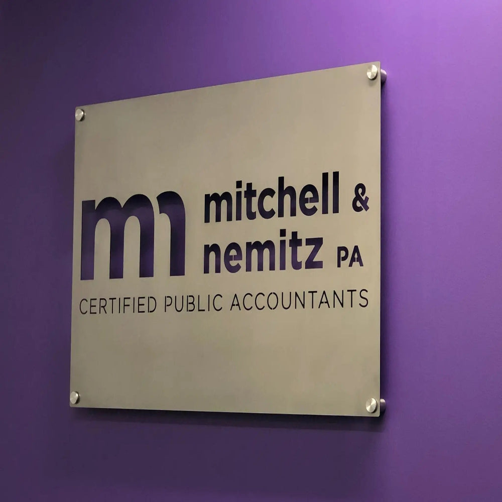 Custom metal wall sign with "mitchell & nemitz PA" text, mounted using standoff spacers on a purple background, ideal for office or business décor and personalized signage.