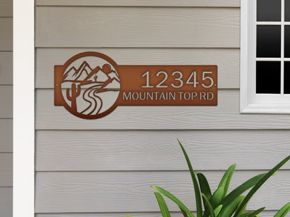 Desert Mountain Monogram Address Plaque featuring elegant metal house numbers and mountain-and-river design, crafted for outdoor durability and personalized home décor, showcased against a textured wall.