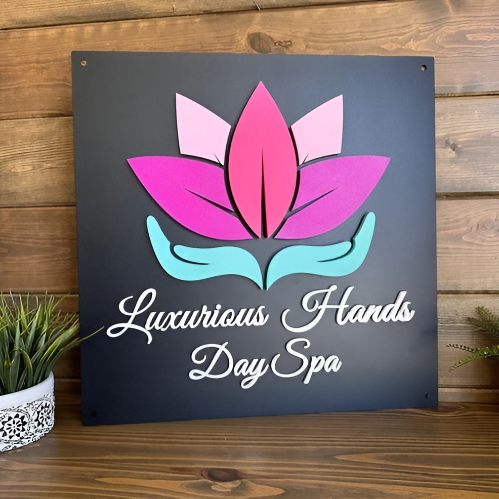 Custom 3D steel business logo sign with pink and blue lotus flower, “Luxurious Hands Day Spa” text, multi-material metal wall art on wood background, personalized spa signage.