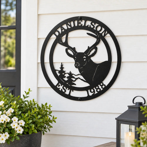 a black metal sign with a deer silhouette and the text "DANIELSON EST 1988" mounted on a white exterior wall.
