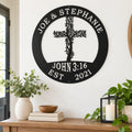 a wall decoration with a tree-like design and a cross, mounted on a wall above a wooden table with various items on it, including a bowl, a candle, and some books.