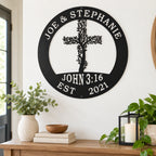 a wall decoration with a tree-like design and a cross, mounted on a wall above a wooden table with various items on it, including a bowl, a candle, and some books.