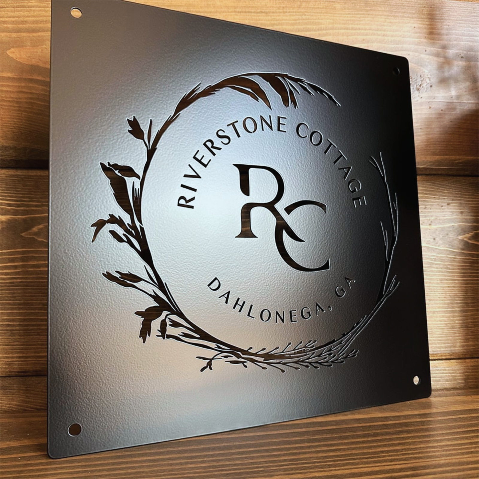 a metal plaque with a logo and text, mounted on a wooden surface.
