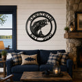 Black bass fish metal wall decor with Newstrom and Est 2020 mounted above a blue sofa in a cozy lake house living room