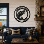Black bass fish metal wall decor with Newstrom and Est 2020 mounted above a blue sofa in a cozy lake house living room