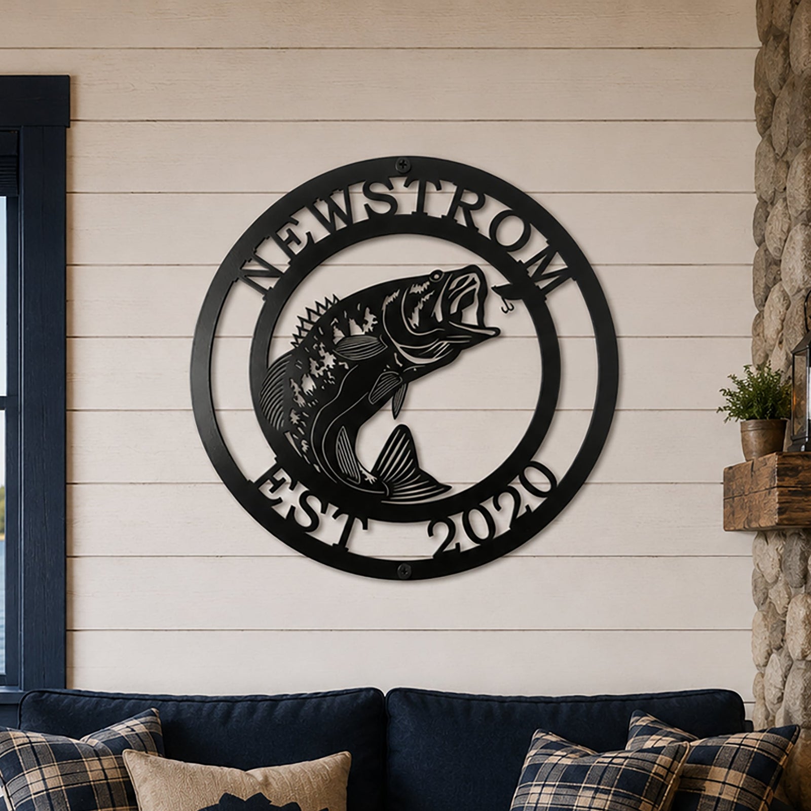 Black bass fish metal wall decor with Newstrom and Est 2020 mounted above a blue sofa in a cozy lake house living room