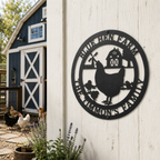 Black personalized chicken farm metal sign with hen and chicks mounted on white barn wall near chicken coop