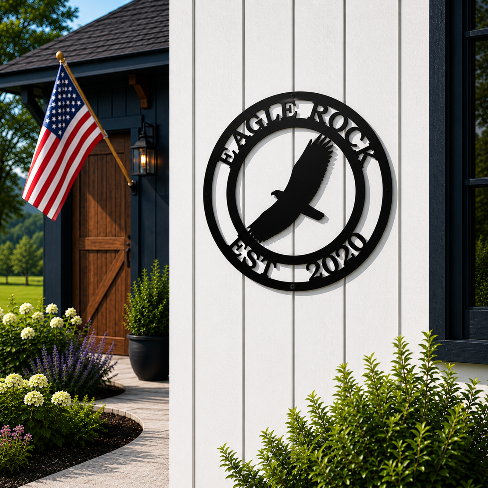 Black Eagle Rock metal sign with soaring eagle design mounted on white farmhouse siding near an American flag