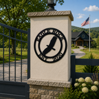 Black Eagle Rock metal sign with flying eagle design mounted on a stone gate pillar near a country driveway