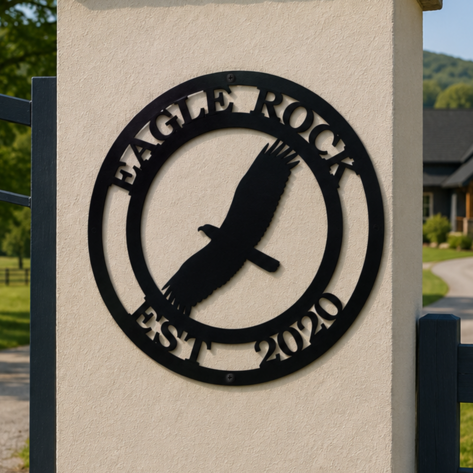 Black Eagle Rock metal sign with flying eagle design mounted on a stone gate pillar near a country driveway