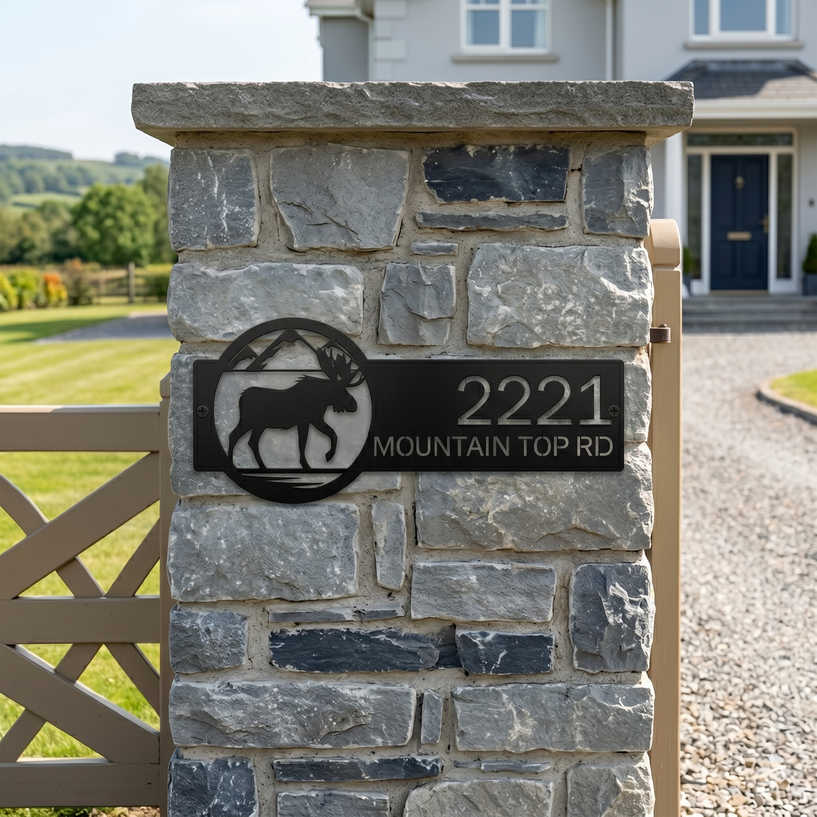 Black moose address sign with mountain design and house number mounted on stone entrance pillar