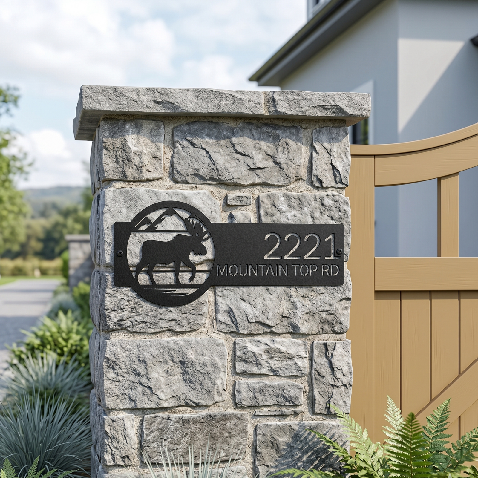 Black metal moose address plaque with house number displayed on stone pillar beside entry gate