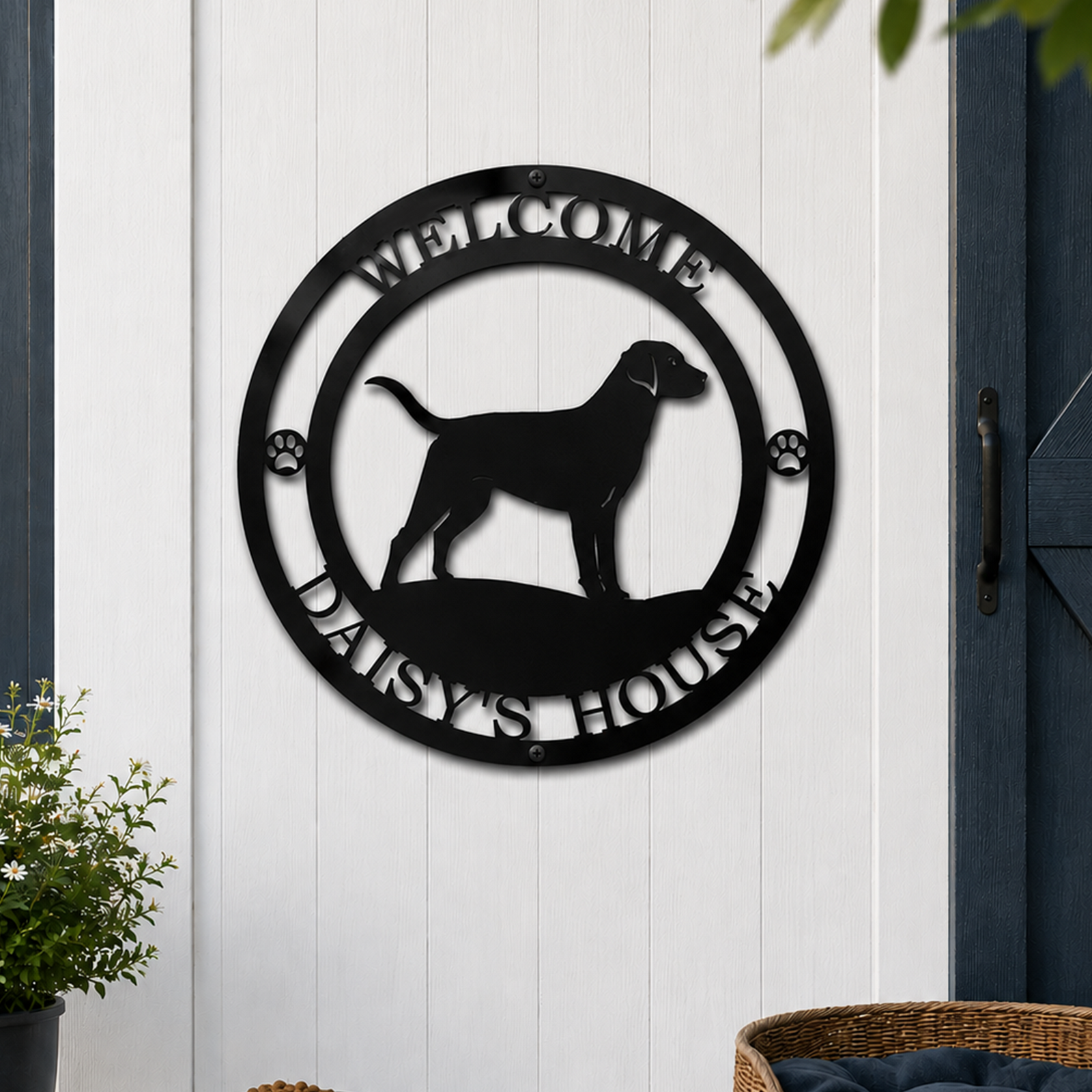 Black personalized dog welcome metal sign mounted on white shed wall beside pet bed and dog bowl displaying Daisy's House text