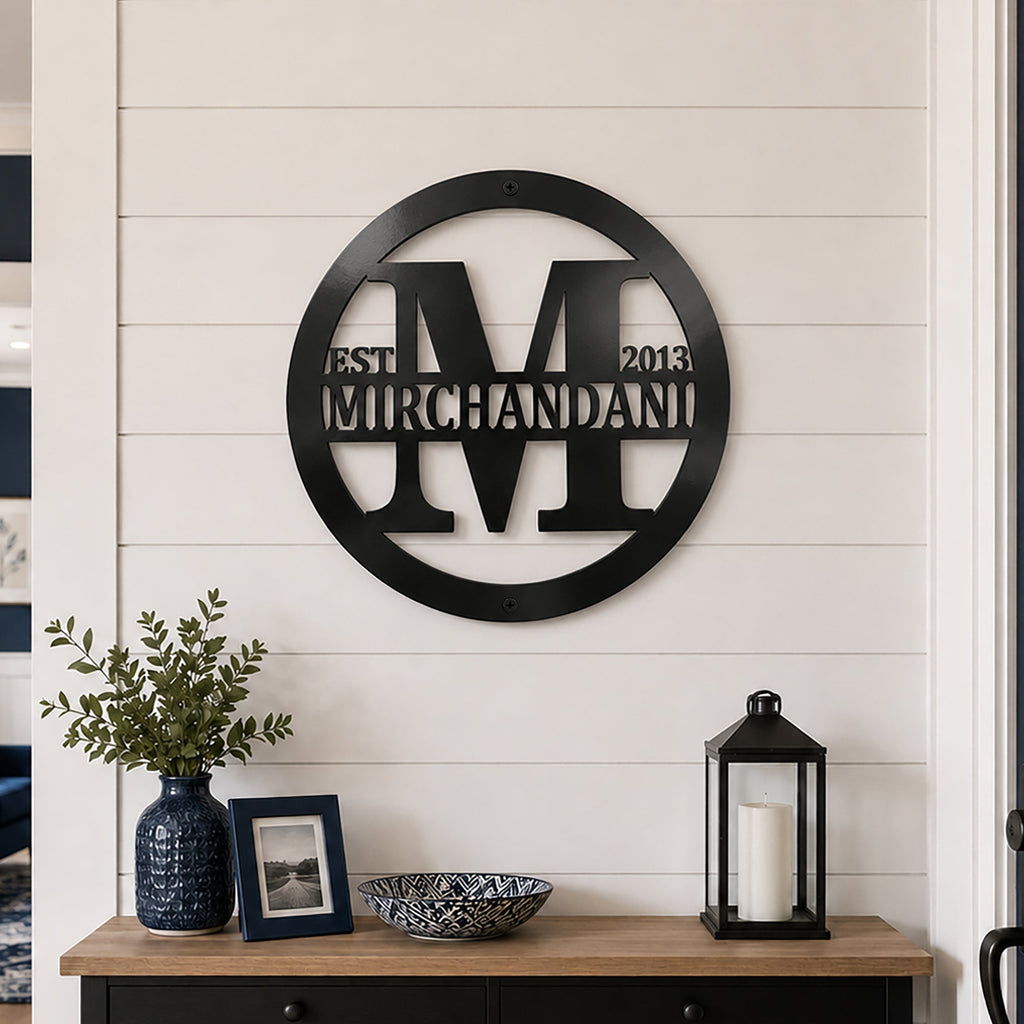 Black custom family monogram metal sign displayed on a white shiplap entryway wall above a console table