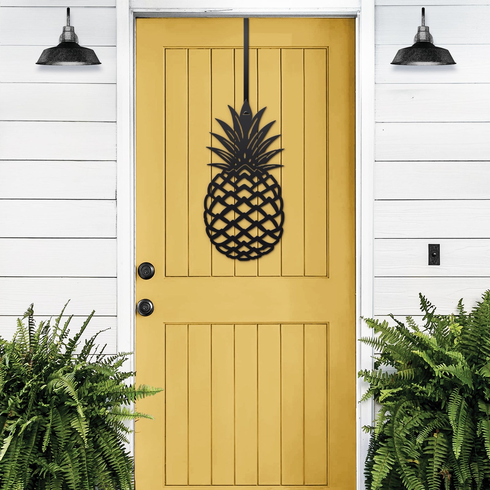 Black pineapple welcome door hanger displayed on yellow front door for tropical porch entry decor