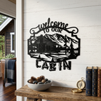 Black welcome to our cabin metal wall art with mountain lodge scene displayed above rustic table decor