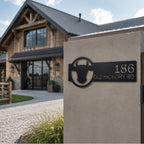 Black western style metal address plaque with bull head design installed on concrete entry wall outside farmhouse