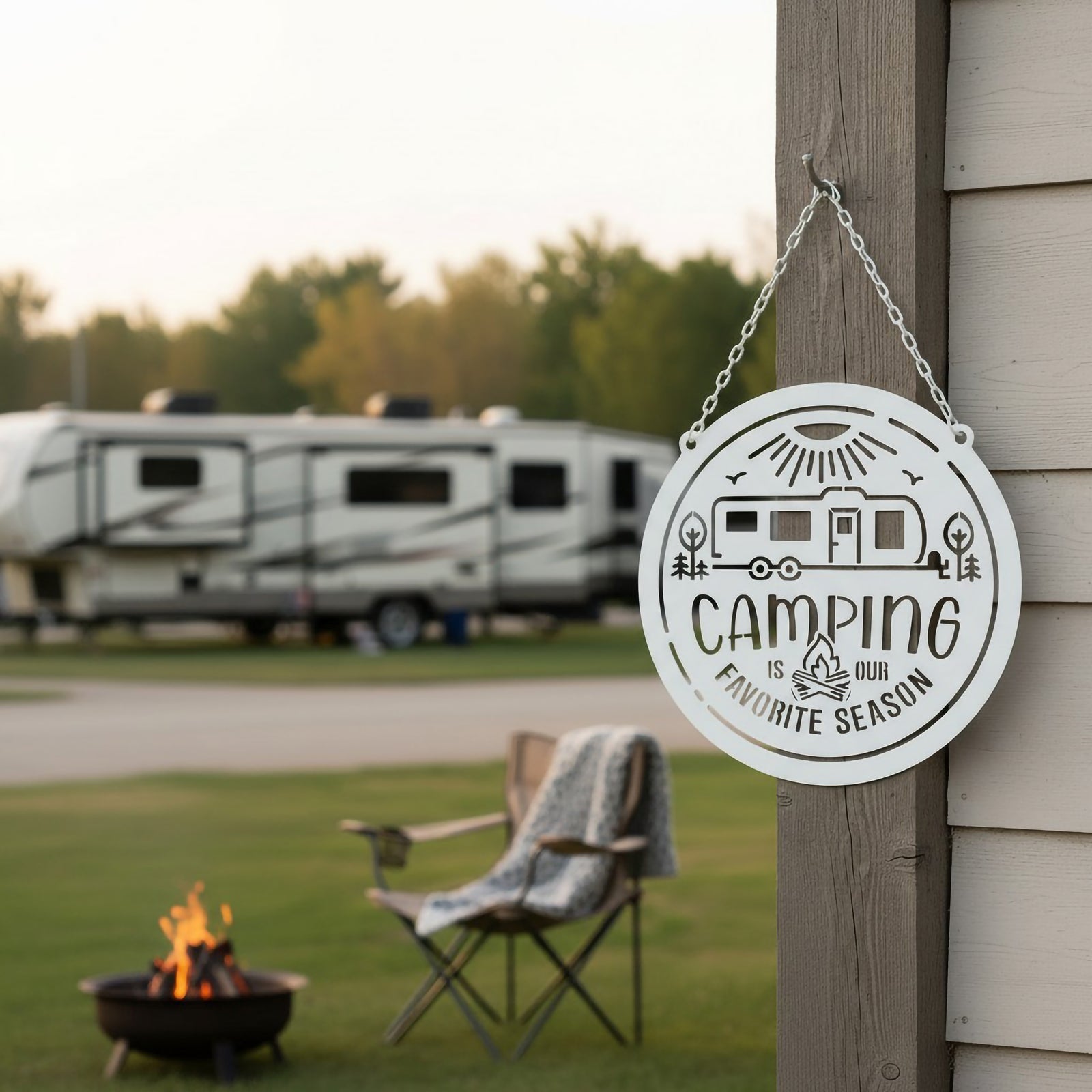 Sky white camping metal sign hanging on a wooden post at a campground with RV trailers and campfire seating in the background.