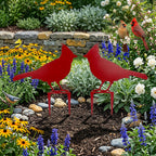 Red metal cardinal garden stakes showcased in vibrant flower garden with blooming plants and decorative stone border