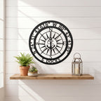 Personalized compass metal wall art displayed on exterior stucco wall with greenery and modern outdoor decor