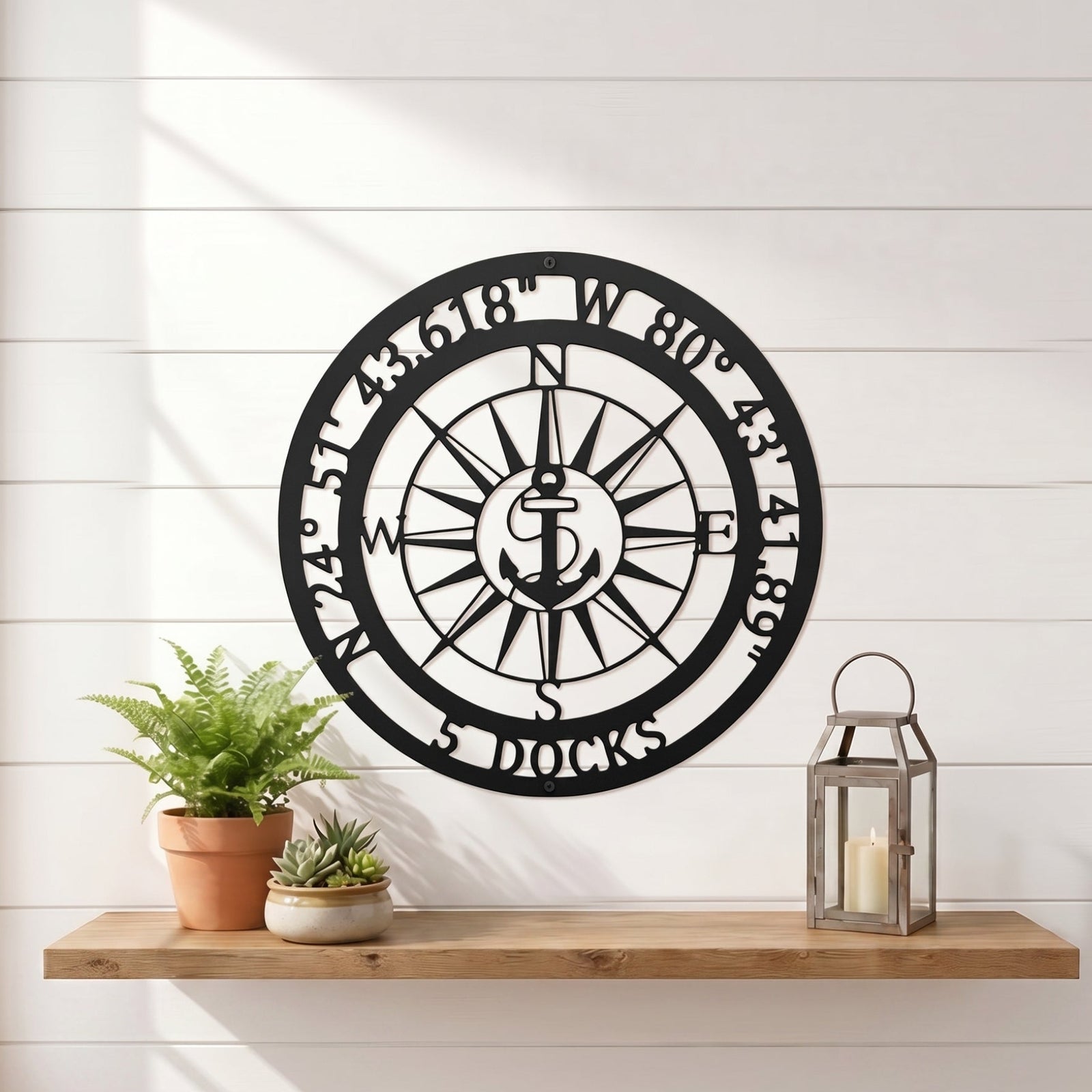Personalized compass metal wall art displayed on exterior stucco wall with greenery and modern outdoor decor