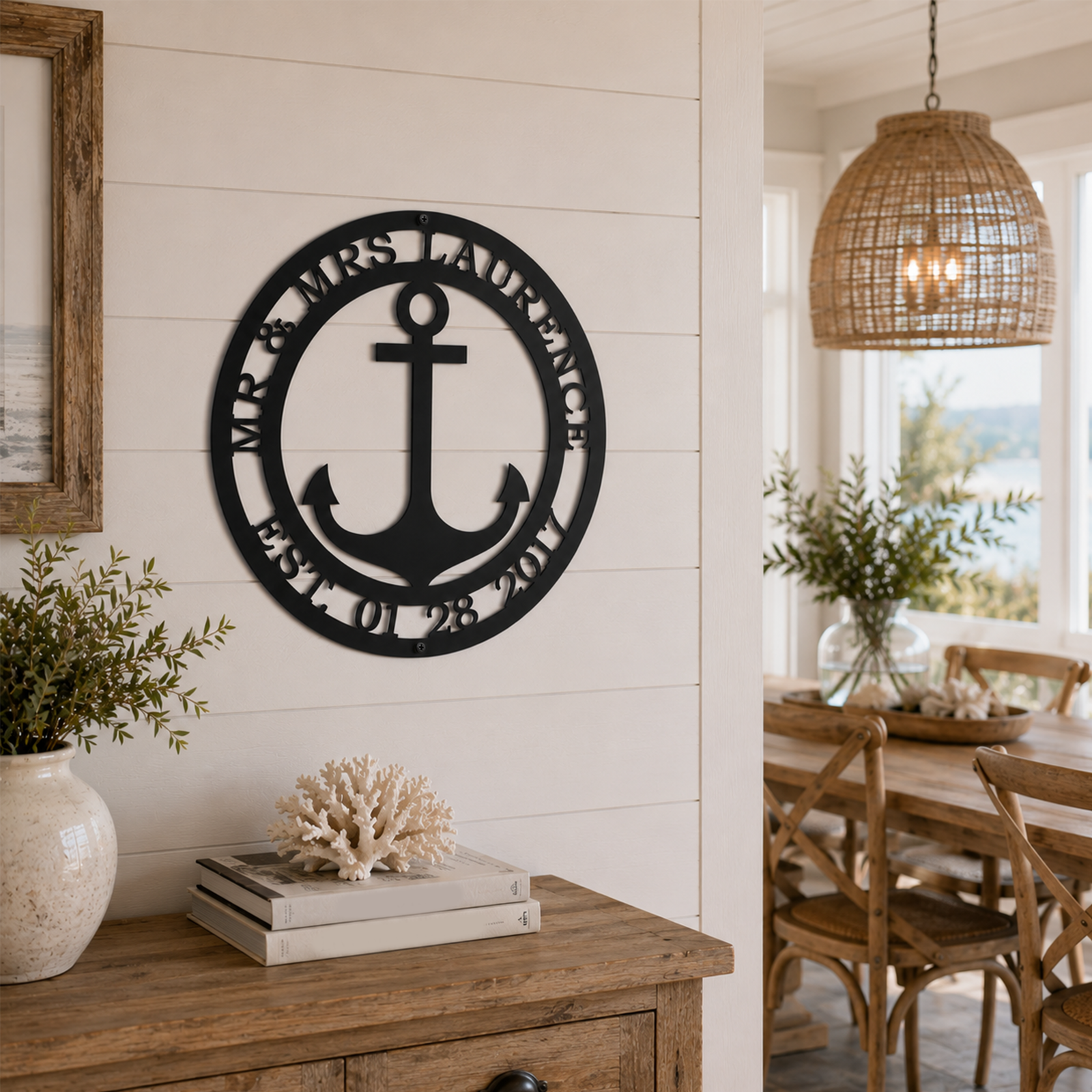 Matte black personalized nautical anchor metal sign with custom text Mr. & Mrs. Laurence Est 01 28 2017 mounted on a white shiplap wall in a modern beach house living room.