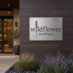 Custom brushed aluminum ACM business logo sign featuring Wildflower Medispa logo mounted on a modern exterior wood facade with landscaping and storefront entrance.