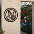 A black circular metal sign that reads "Stephanie's Rose Garden" with an intricate butterfly and rose design, mounted on a white wooden fence next to an open decorative iron gate.