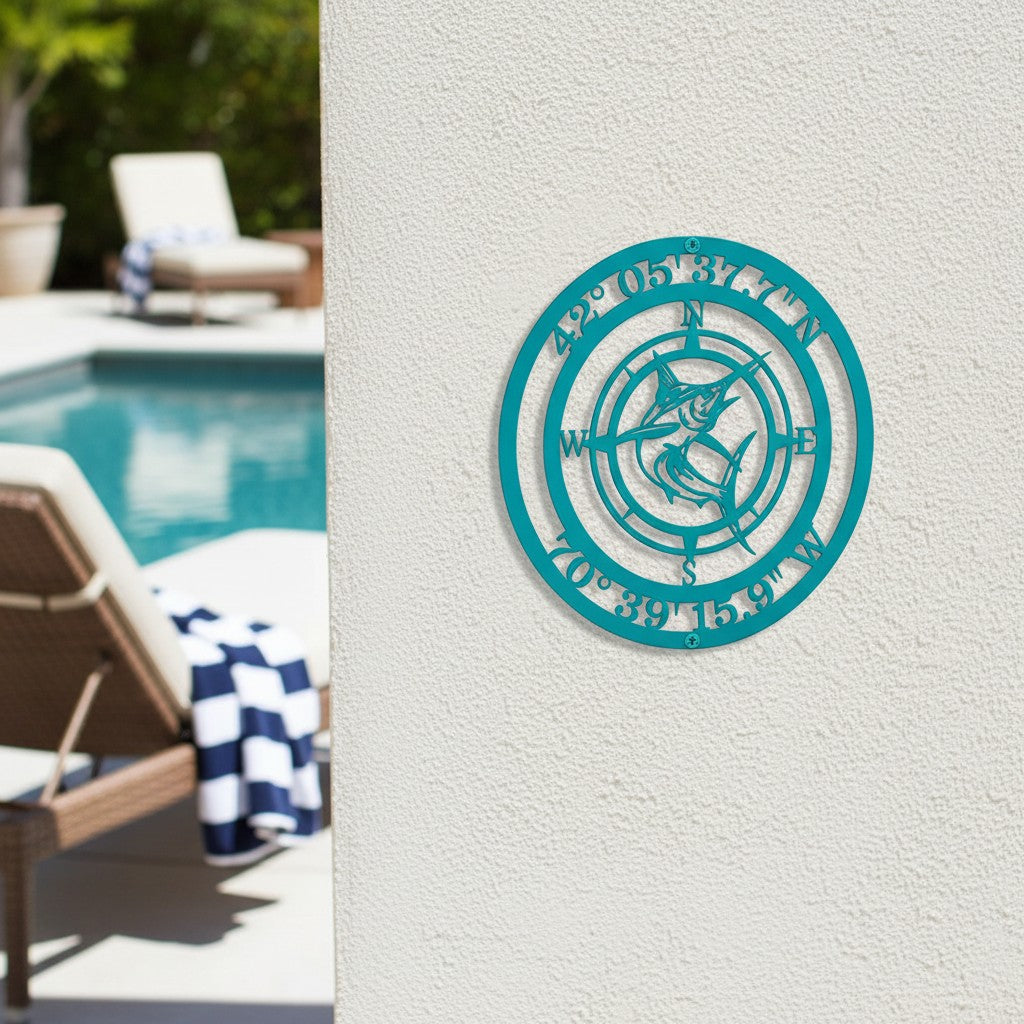 Custom Marlin Fish Compass Metal Medallion in teal mounted on a white stucco wall by a luxury poolside setup with lounge chairs
