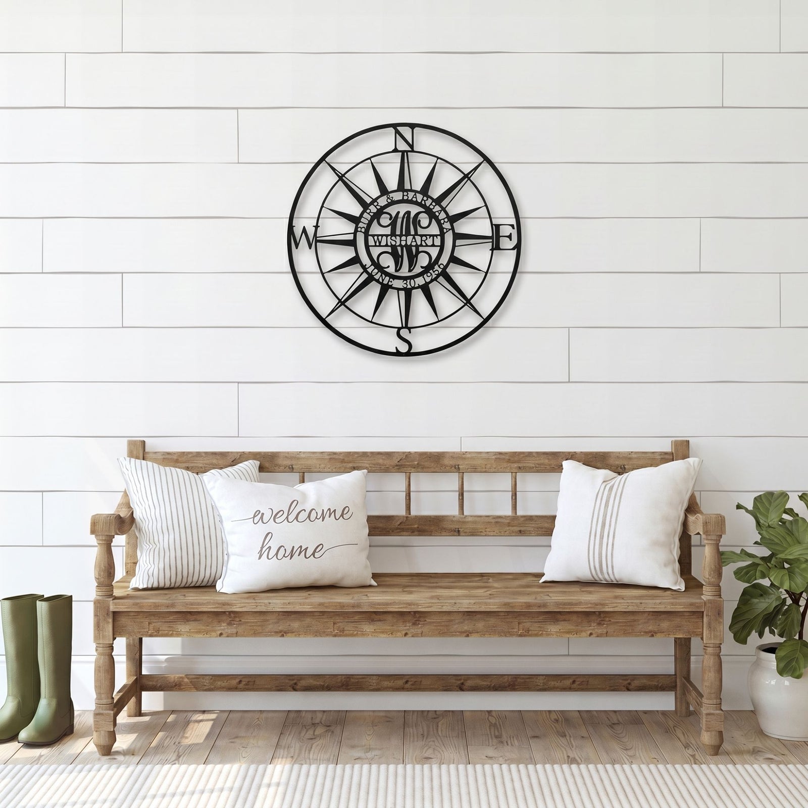 Personalized compass rose metal wall sign displayed above rustic wooden bench in farmhouse entryway