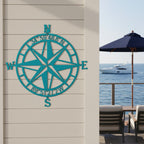 Custom compass rose metal sign — personalized turquoise beach house decor featuring custom GPS coordinates displayed on a waterfront patio.