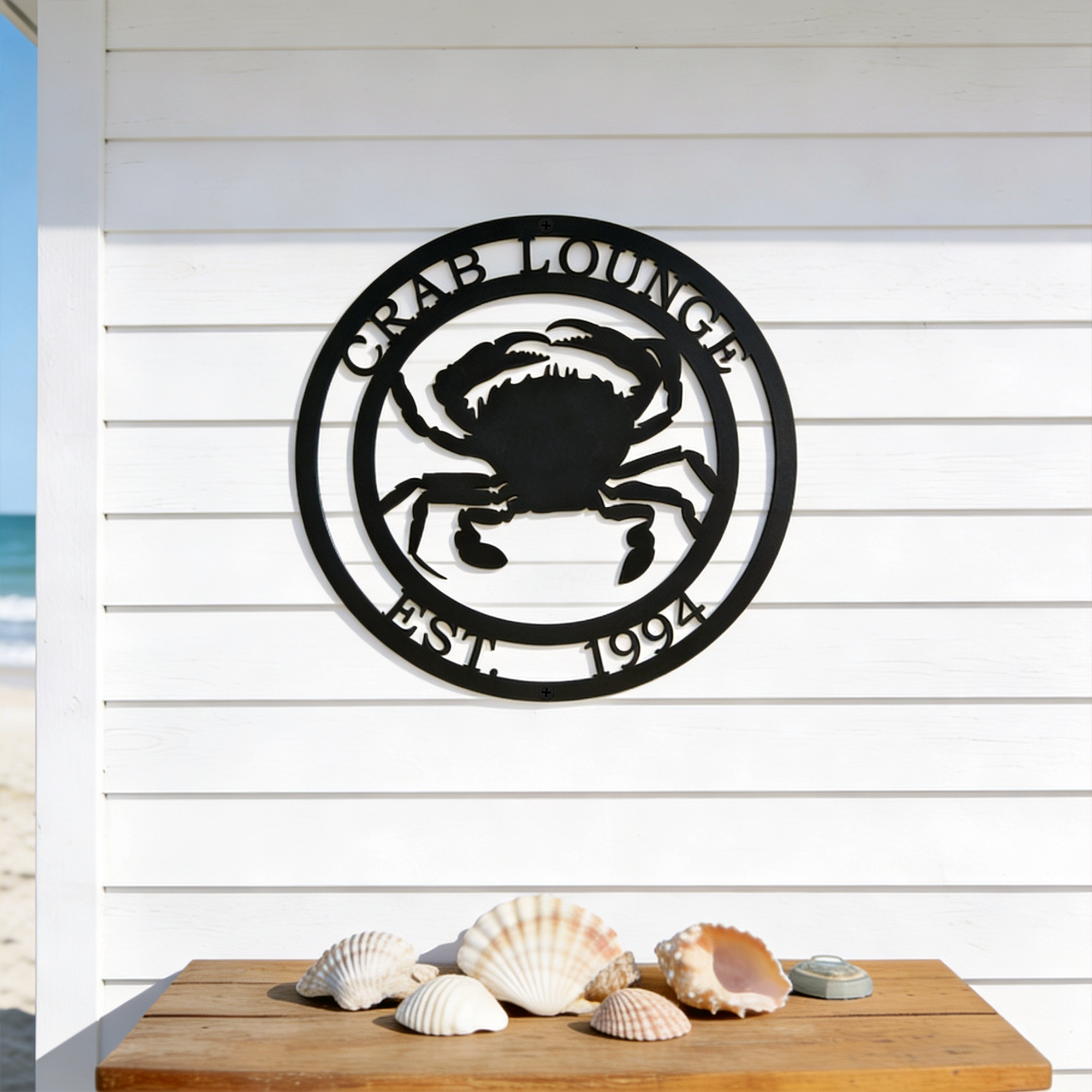 Black crab lounge metal sign with crab design displayed above seashell table decor