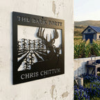 Satin black custom deer and cornfield metal sign displayed on farmhouse exterior with garden and blue barn