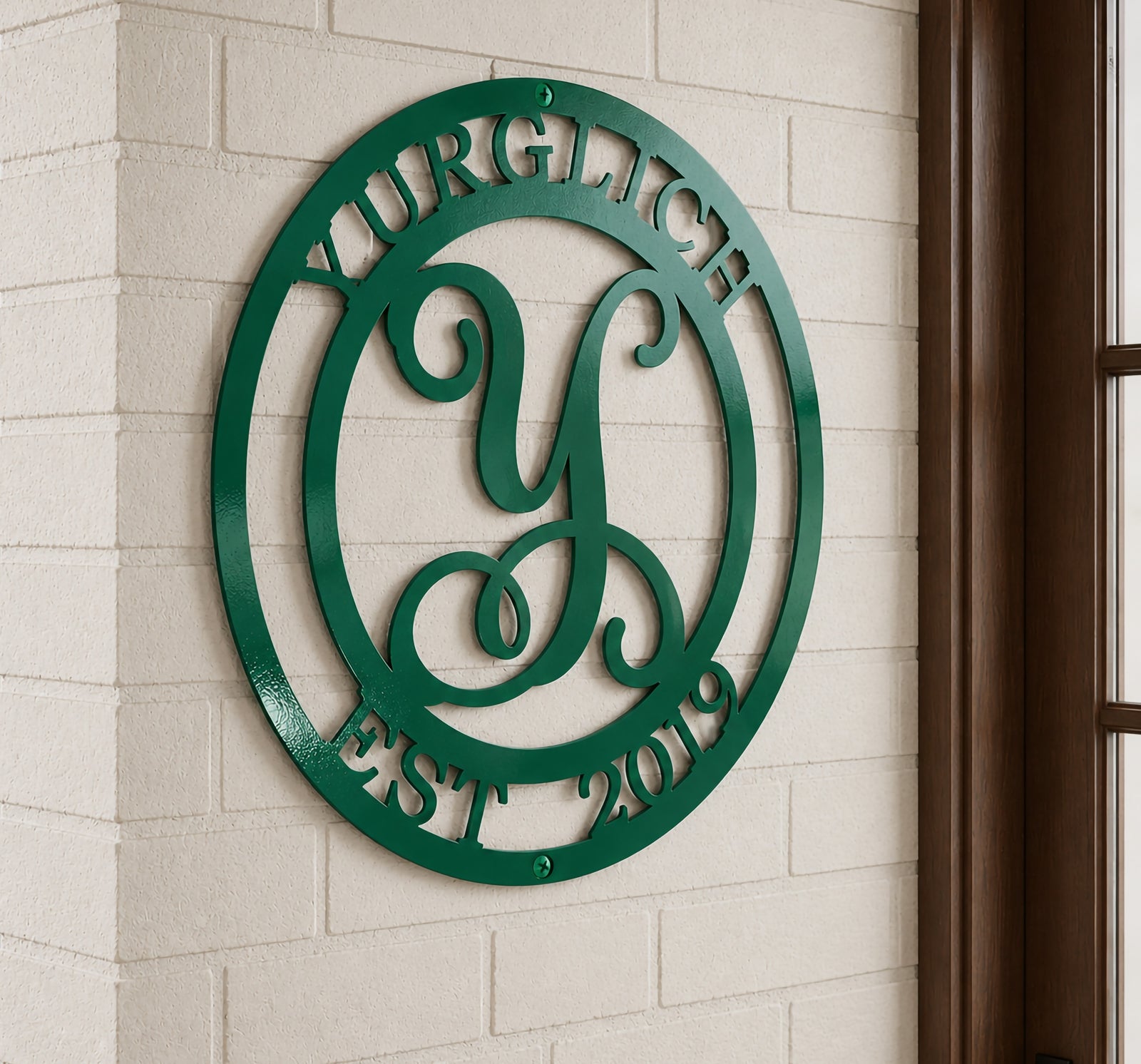 Glossy emerald green variation of the personalized family initials metal sign mounted on a white brick pillar next to a dark wood window frame.