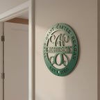 Custom Emerald Green family monogram metal sign with personalized names, surname, and established date mounted on a neutral interior wall.