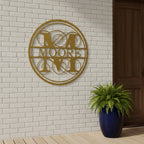 Custom family monogram metal sign — personalized gold last name wall decor mounted on a white brick wall near a front entryway.