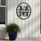 Custom family monogram metal sign — personalized outdoor monogram wall sign in black powder-coated steel displayed on exterior board and batten siding.