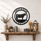 Black livestock metal wall sign with cattle silhouette and custom farm name displayed above rustic farmhouse shelf décor