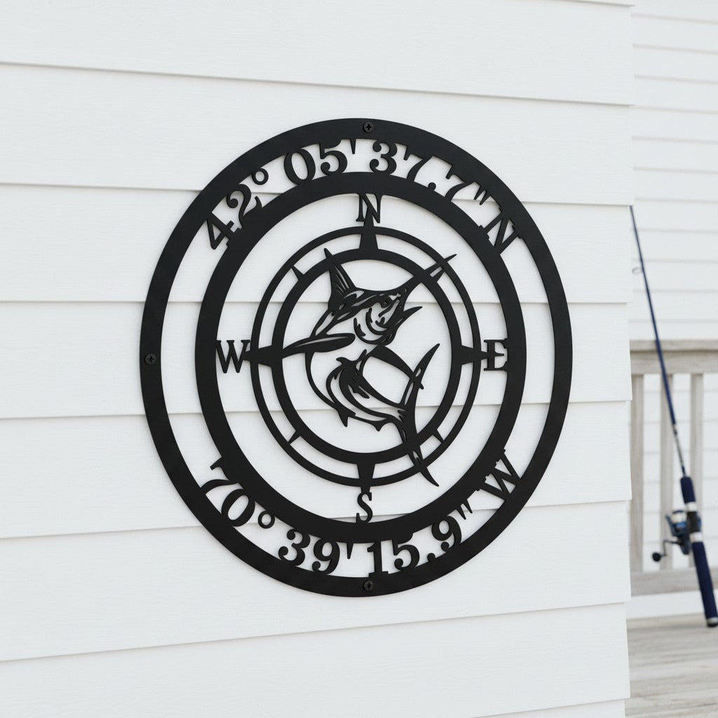 Custom Fishing Coordinates Compass Metal Wall Plaque in matte black color displayed on a white lap siding wall next to a fishing rod