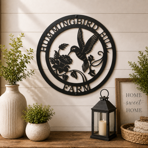 Personalized hummingbird farm metal wall décor with floral accents displayed above wooden table with lantern and plants