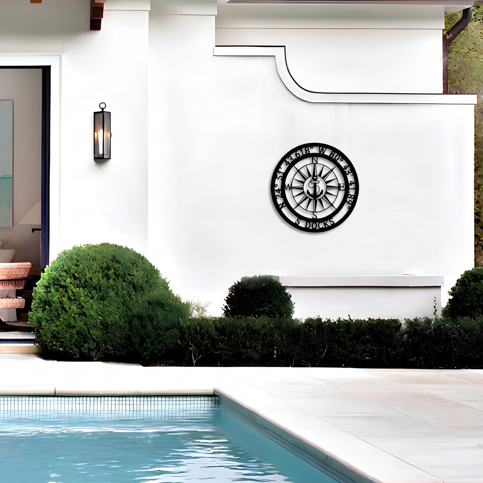 Personalized nautical compass metal wall decor displayed beside modern outdoor pool and white exterior wall